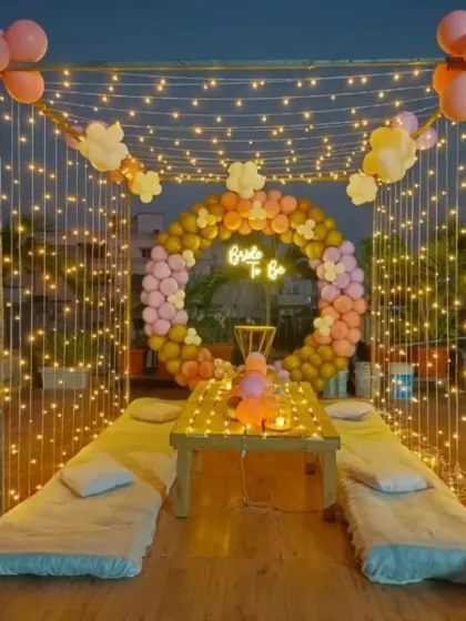 Here is a complete cabana-style seating arrangement for a rooftop party. I used a frame draped with fairy lights, a 'Bride to Be' neon sign, and a balloon ring to create a cozy and picture-perfect space for a bridal shower.