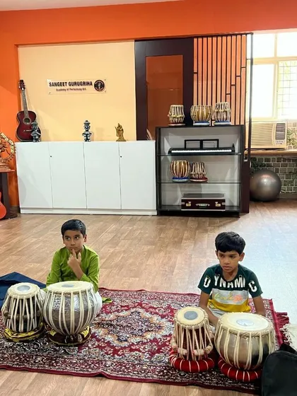 Two of our youngest students sit with their tablas, ready for their music lesson. We welcome learners of all ages, nurturing their passion for Indian classical music from the very beginning.