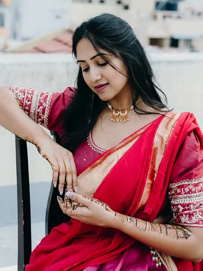A serene shot of the client, her red saree contrasting beautifully with the intricate henna on her arms.
