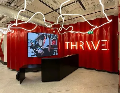 The reception area of the DLF Thrive gym, where dynamic design energizes the space. We used bold red corrugated walls, a sculptural reception desk, and custom 'noodle' lighting to create an immersive and motivating entry experience for members.