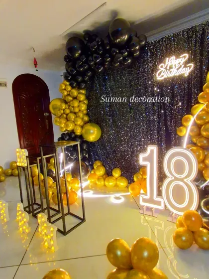 Here’s a sleek and stylish 18th birthday party decoration. The theme uses a bold black and gold color scheme with a shimmering sequin backdrop, a large balloon garland, and light-up marquee numbers for a glamorous look.