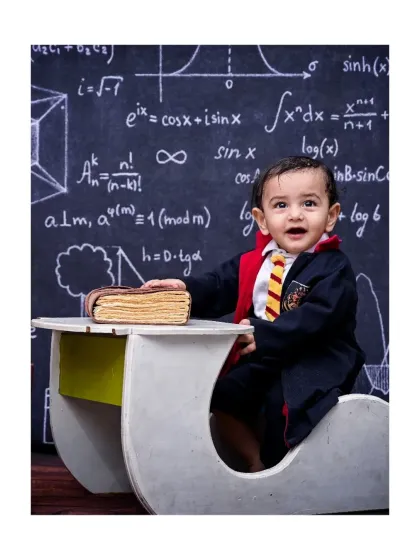 A happy future wizard, dressed in his house colors and sitting at a desk in front of a chalkboard of equations. This Harry Potter themed shoot is a great example of how I bring popular stories to life for your little one.