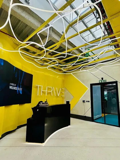 The reception of the DLF Thrive Gym in Chennai is designed to energize. The vibrant yellow, a nod to the city's spirit, combines with dynamic 'noodle' lighting and a sleek, curved desk to create a high-impact welcome for a state-of-the-art fitness experience.