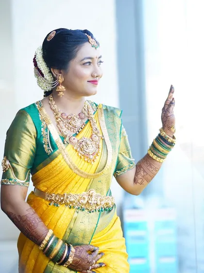 A candid moment of the bride looking out a window, her henna-decorated hands adding to her grace and elegance.