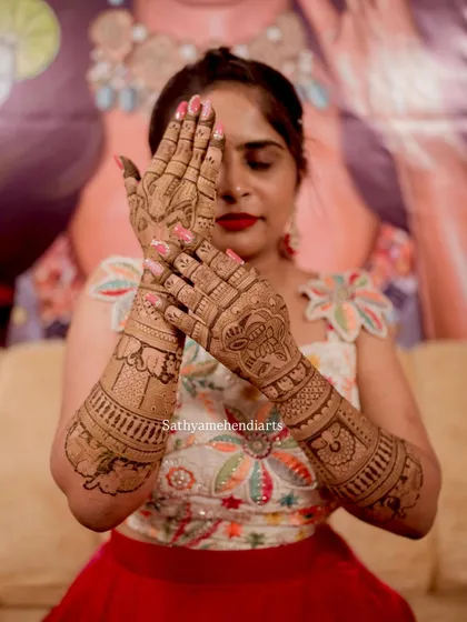 A beautiful pose showing off the intricate details of her wedding mehendi. The design covers her hands and forearms completely.