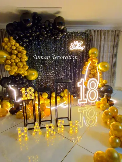 A stylish black and gold theme for an 18th birthday celebration. This setup features a black sequin wall, a "Happy Birthday" neon sign, large marquee numbers, and a dramatic balloon arch, perfect for creating a glamorous party atmosphere.