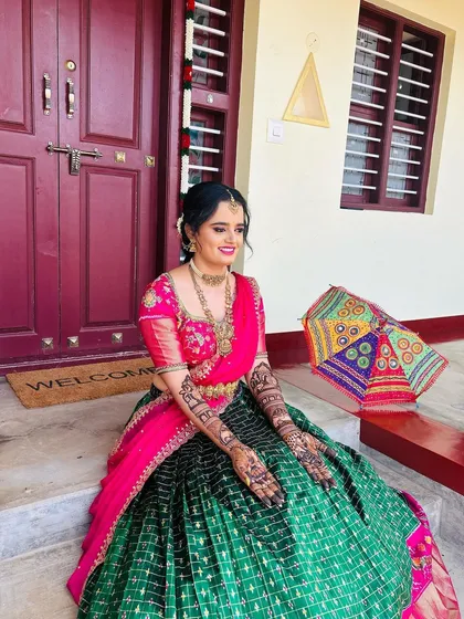 A full-length shot of the bride sitting gracefully, her intricate mehendi visible as a key part of her festive ensemble.