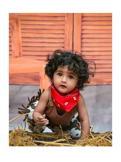 Meet the cutest little cowboy in town. This themed portrait session uses a rustic backdrop, hay, and a classic red bandana to create a unique and memorable baby photoshoot.