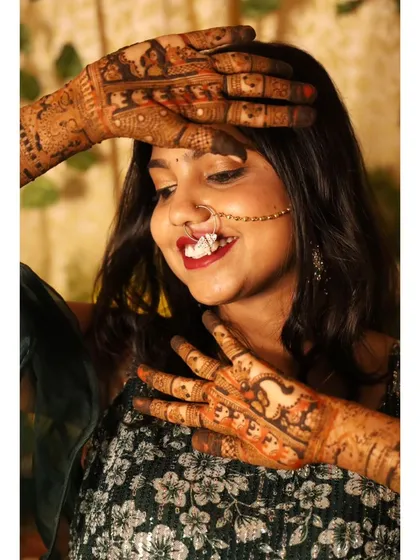 A lovely pose where the bride's hands highlight her face and jewelry, with the rich mehendi stain adding to her festive look.