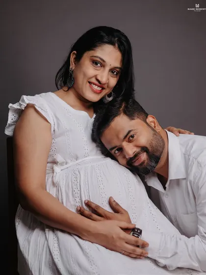 The joy of expecting, captured in a classic studio portrait. This intimate pose shows the beautiful connection between a couple, with simple lighting that focuses all the attention on them.