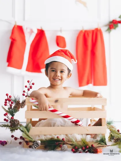 The perfect holiday portrait. This close-up from a Christmas themed session shows a happy boy in a Santa hat, holding a candy cane in a festive, custom-designed crate setup.