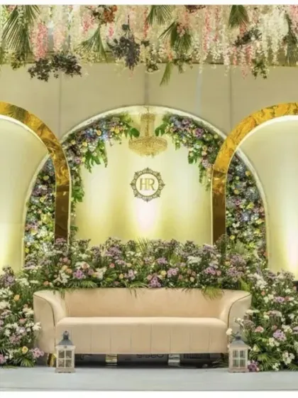 This reception stage is all about modern elegance. We used gleaming golden arches of varying heights, framing the central seating area. The arches are decorated with lush, pastel-colored floral arrangements, creating a sophisticated and romantic ambiance perfect for a contemporary wedding.