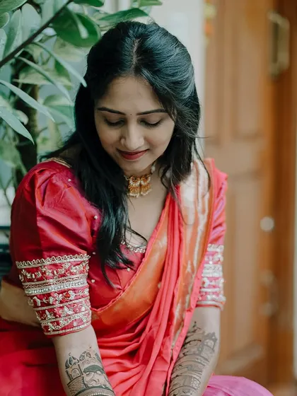 A close-up shot showing the details of the mehendi on her arms as she sits gracefully.